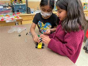 two third graders work on creating a Lego car that moves using magnetic forces